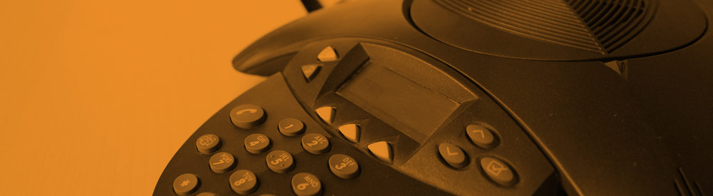 Orange-tinted office conference phone on a desk — banner imagery from the FHG homepage What-If? carousel, 2015-2017.
