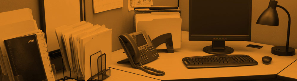 Orange-tinted photo of a busy office desk with file folders, a 2007 binder, and a desk phone — banner imagery from the FHG homepage What-If? carousel, 2015-2017.